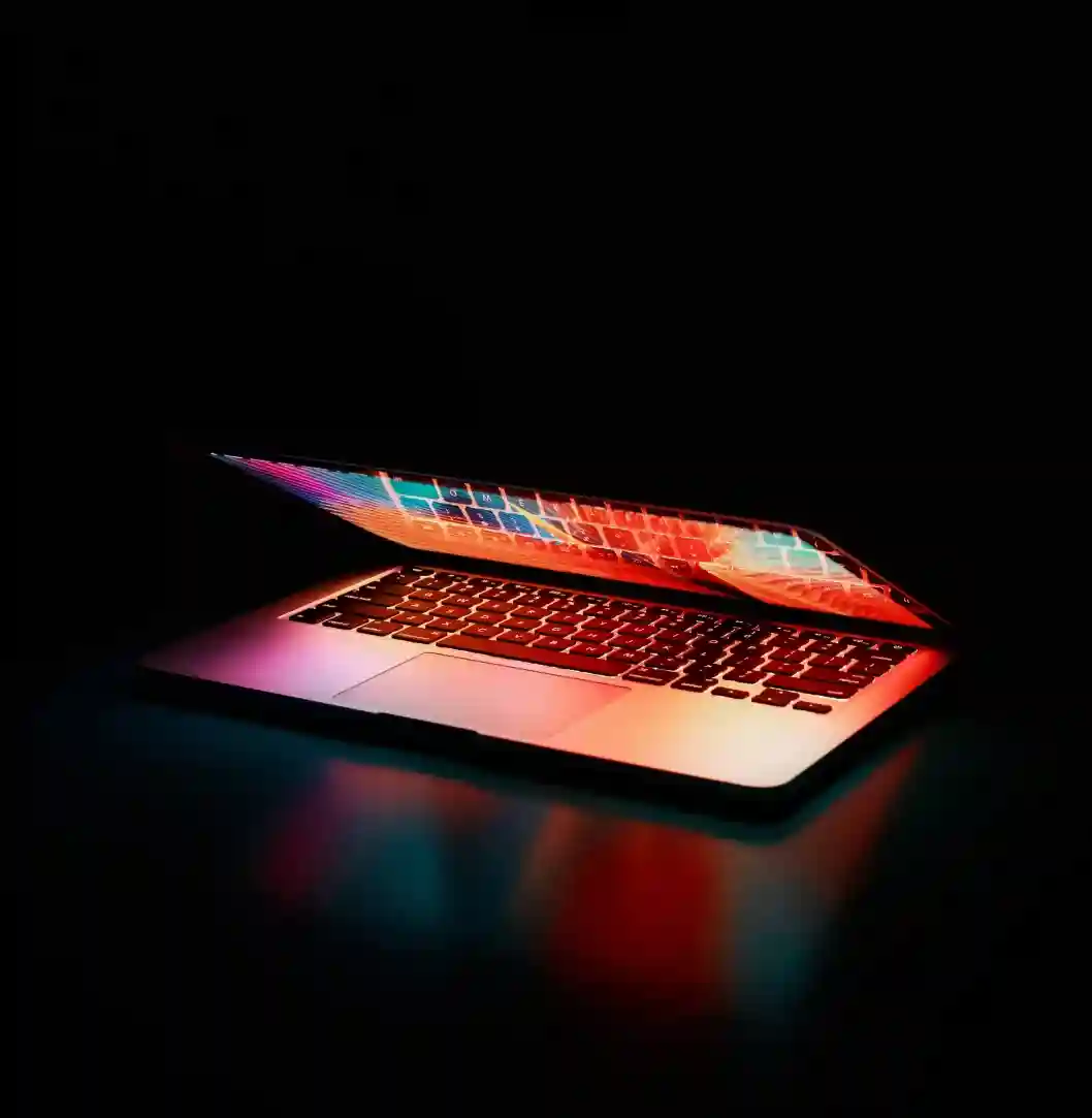 Laptop glowing with colorful light in dark.